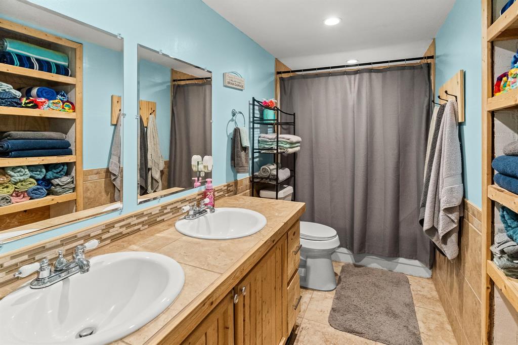 108 Paige Street Weatherford, TX 76088 - Photo 22 of 34 a bathroom with a granite countertop sink and a mirror a toilet