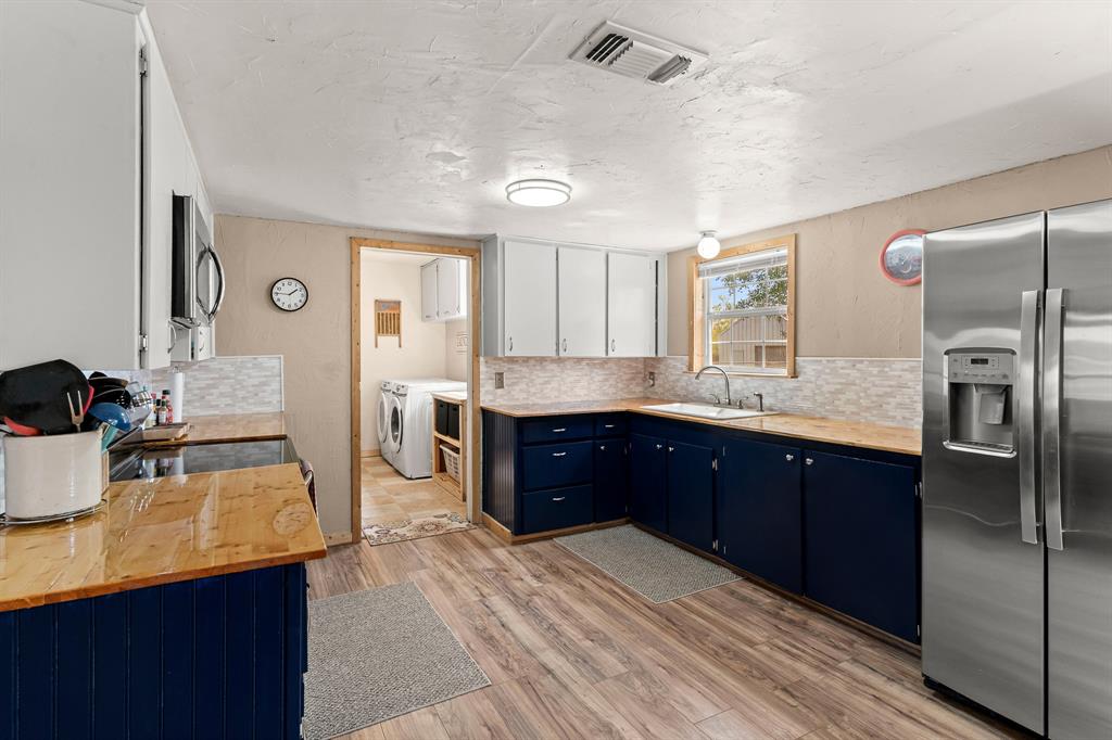 108 Paige Street Weatherford, TX 76088 - Photo 9 of 34 a kitchen with stainless steel appliances granite countertop a refrigerator a sink dishwasher and wooden cabinets with wooden floor