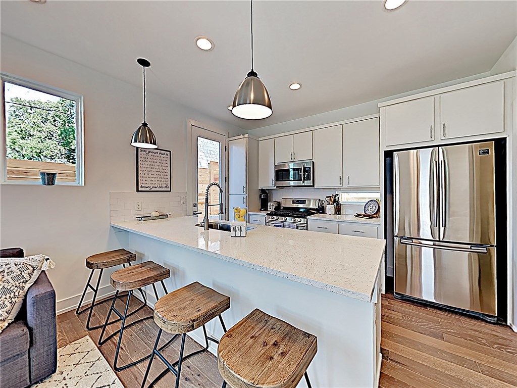 5314 Downs Drive, Unit A Austin, TX 78721 - Photo 6 of 19 a kitchen with stainless steel appliances a refrigerator a stove a sink a center island a dining table and chairs with wooden floor
