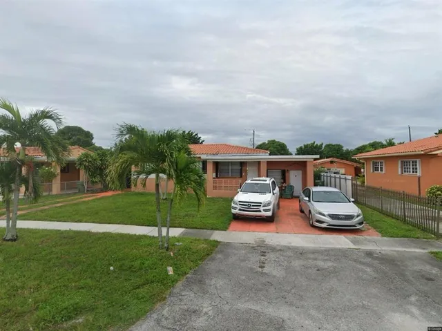 a front view of a house with a garden and trees
