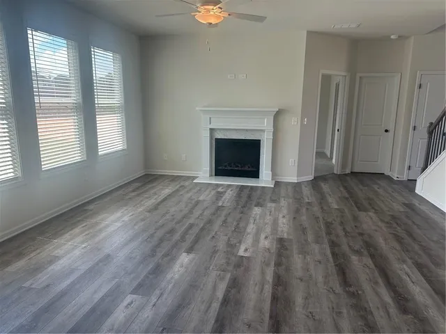 an empty room with wooden floor a fireplace and windows
