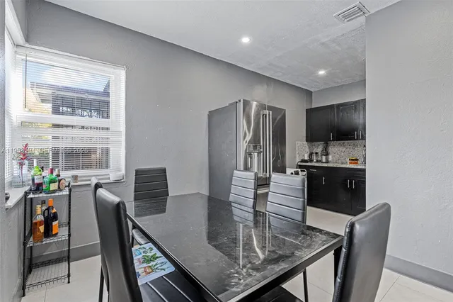 a kitchen with stainless steel appliances granite countertop a stove a refrigerator a kitchen island a table and chairs