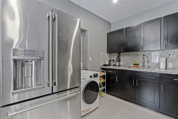 a kitchen with stainless steel appliances granite countertop a sink and a refrigerator