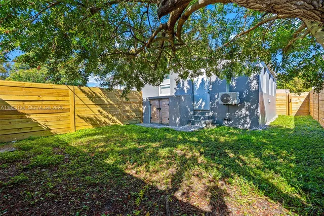 a view of a yard with plants and large trees
