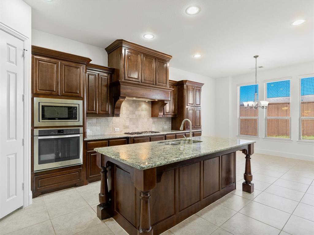 13192 Mapleton Drive Frisco, TX 75035 - Photo 10 of 40 a kitchen with stainless steel appliances granite countertop a stove a sink and a refrigerator