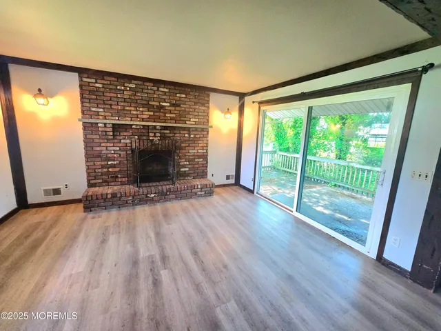 a view of empty room with wooden floor and fireplace
