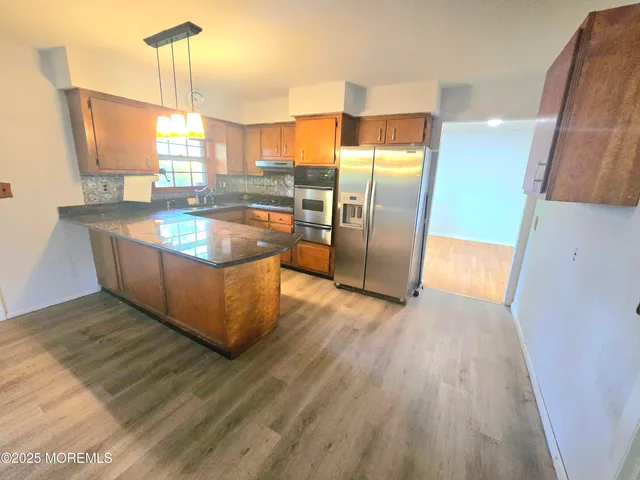 a kitchen with stainless steel appliances granite countertop a refrigerator a sink and a stove