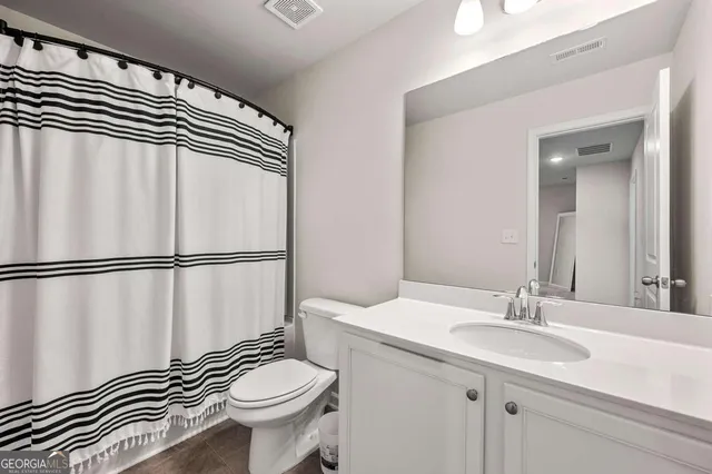 a bathroom with a sink a toilet a mirror and shower curtain