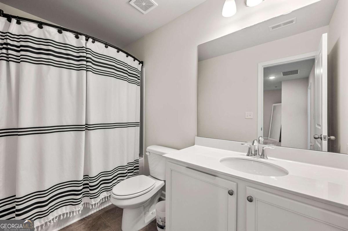 6372 Rosetta Drive Atlanta, GA 30331 - Photo 17 of 26 a bathroom with a sink a toilet a mirror and shower curtain