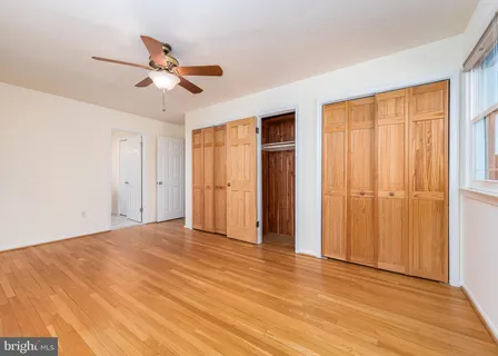 a view of empty room with wooden floor and fan