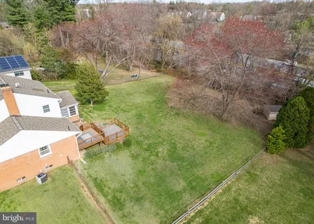 a view of a white house next to a yard with big trees