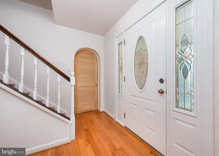 a view of front door with hallway and wooden floor