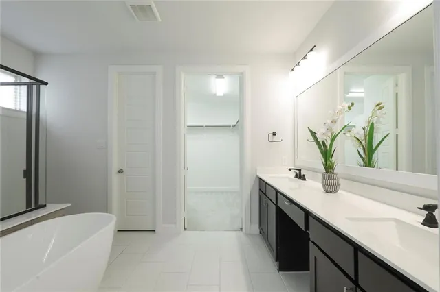 a bathroom with a double vanity sink a mirror and a bathtub