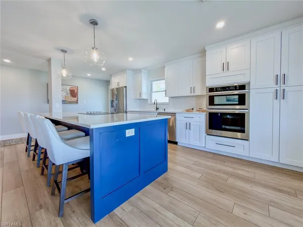 a kitchen with stainless steel appliances kitchen island granite countertop a stove top oven a sink dishwasher and cabinets with wooden floor