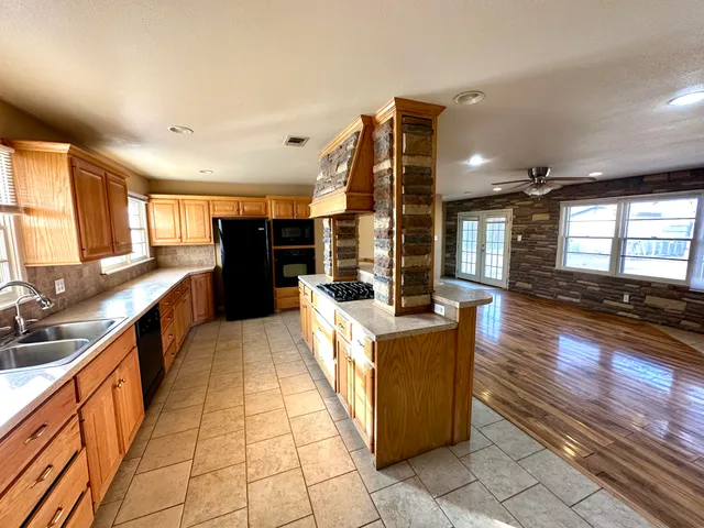 a large kitchen with stainless steel appliances kitchen island granite countertop a large counter top and a stove