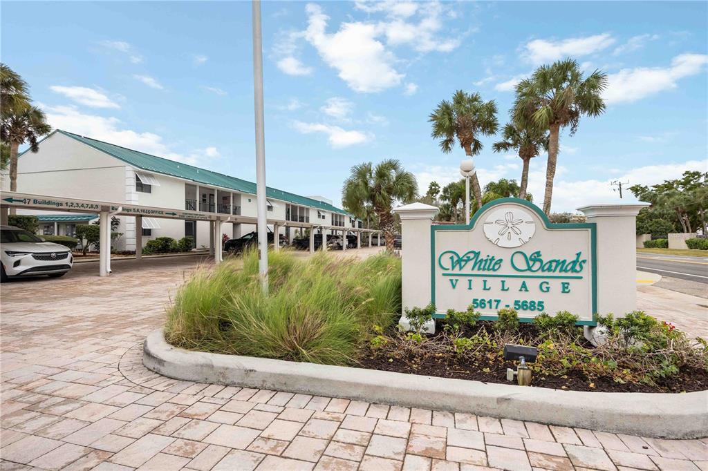 5631 Midnight Pass Road, Unit 1002 Sarasota, FL 34242 - Photo 5 of 30 a front view of a multi story residential apartment building with yard and bench