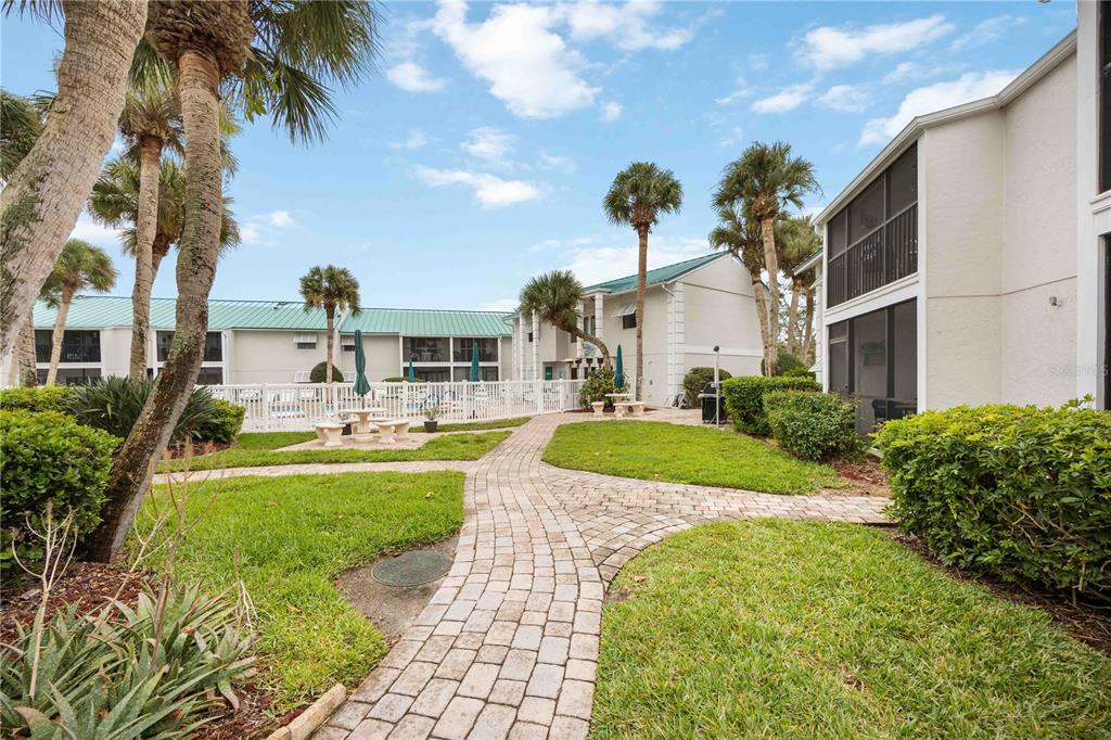 5631 Midnight Pass Road, Unit 1002 Sarasota, FL 34242 - Photo 6 of 30 a view of a white house with a big yard and potted plants