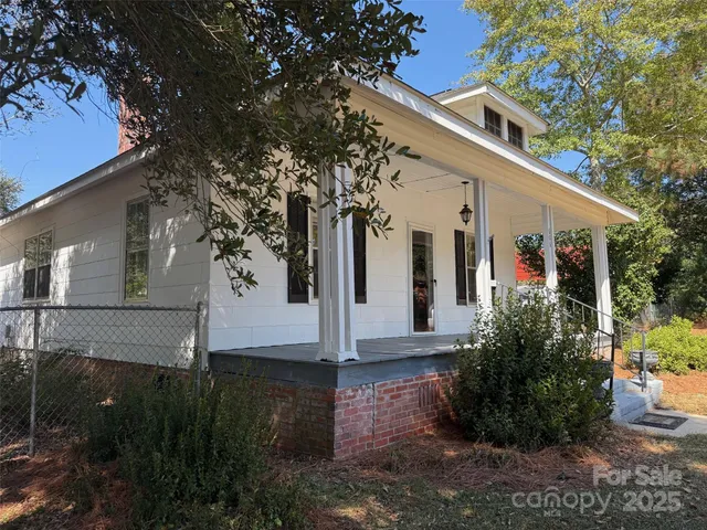 a view of a white house with a yard and potted plants