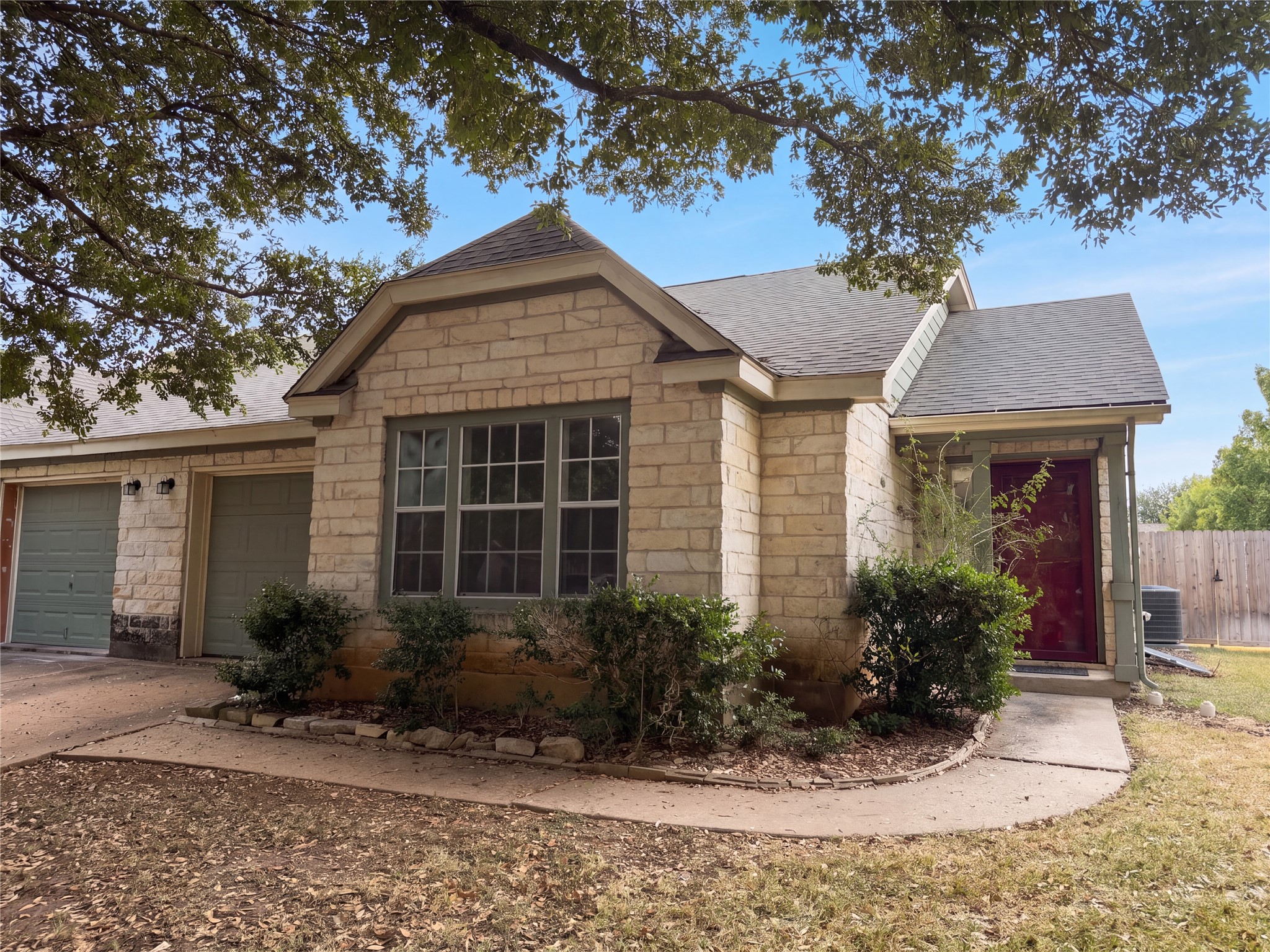 Mature trees shade a classic stone exterior with a welcoming entryway and multi-car garage.