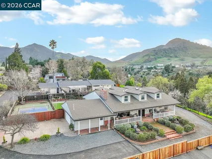an aerial view of a house with swimming pool and mountains