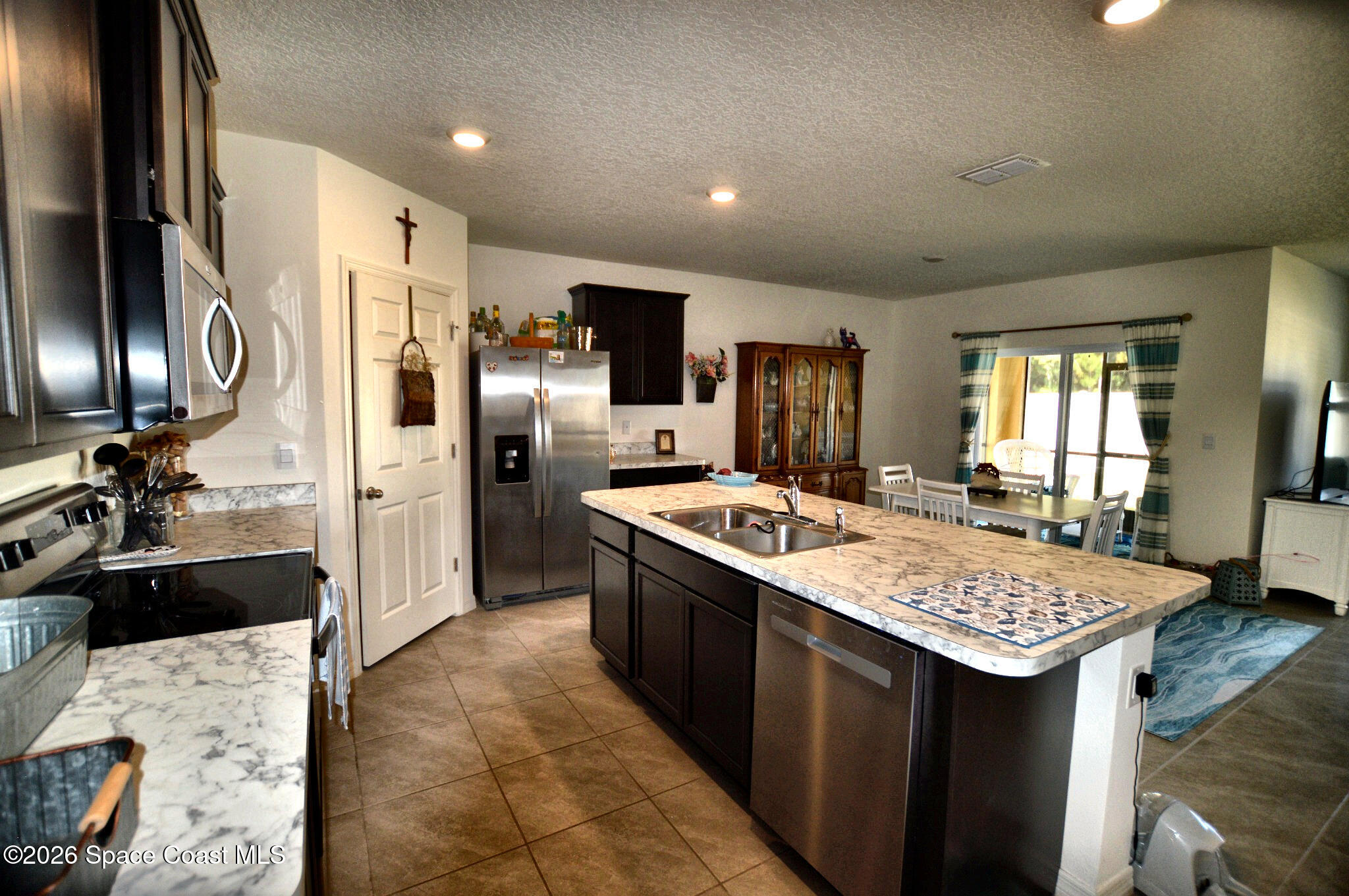 977 Trinity Street Rockledge, FL 32955 - Photo 7 of 18 a kitchen with kitchen island granite countertop a sink stainless steel appliances and refrigerator