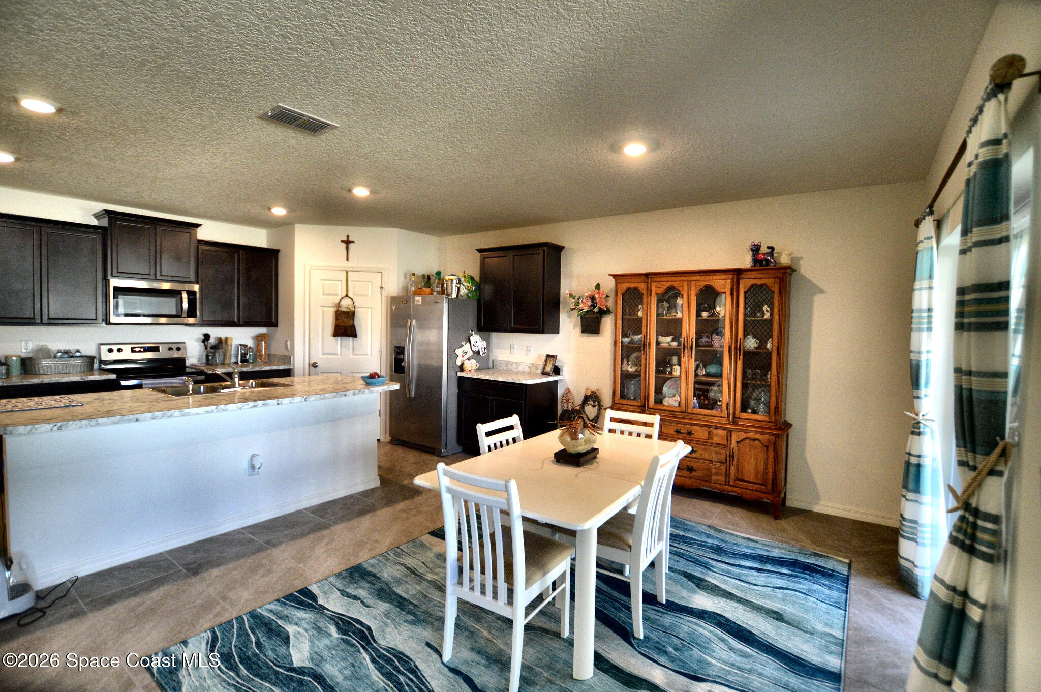 977 Trinity Street Rockledge, FL 32955 - Photo 9 of 18 a kitchen with a table chairs refrigerator and a microwave
