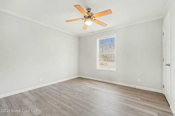 an empty room with wooden floor and ceiling fan