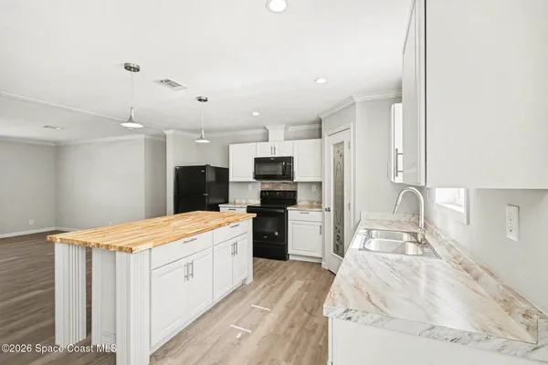 a large white kitchen with a refrigerator a stove top oven a sink dishwasher and wooden cabinets