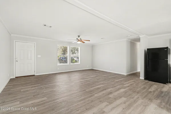 an empty room with wooden floor cabinet and windows