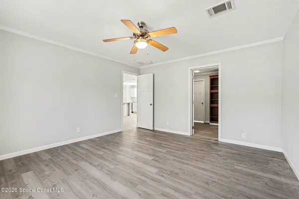 an empty room with wooden floor and ceiling fan