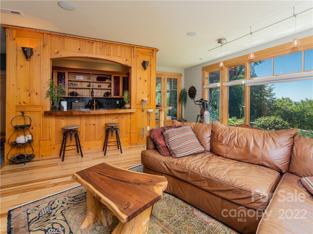168 Pinkerton Corner Fairview, NC 28730 - Photo 33 of 48 a living room with furniture a flat screen tv and a floor to ceiling window