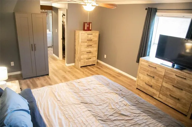 a bedroom with a bed and dresser with wooden floor