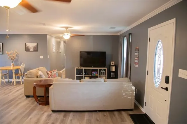 a living room with furniture a flat screen tv and a wooden floor