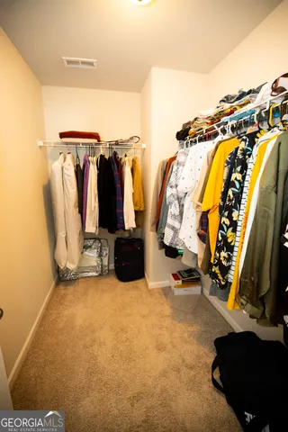 a view of walk in closet with clothes and shoes