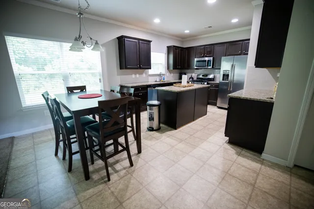 a kitchen with stainless steel appliances granite countertop a stove a sink a microwave a dining table and chairs