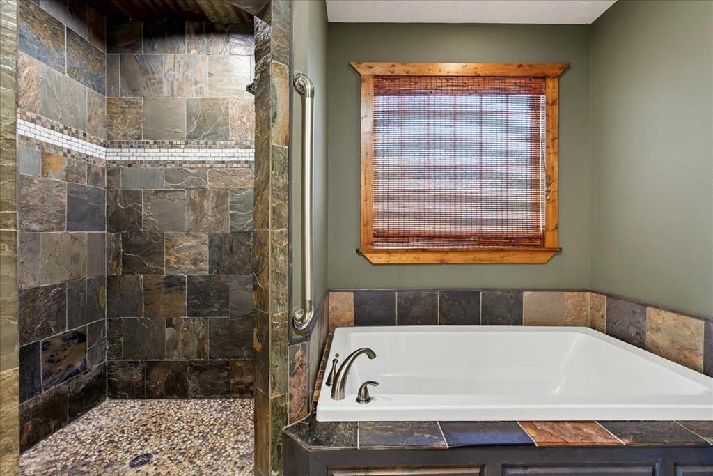 11591 Farm To Market 59 Athens, TX 75751 - Photo 15 of 40 Walk-in shower with natural stone tile and pebble flooring, oversize soaker tub.