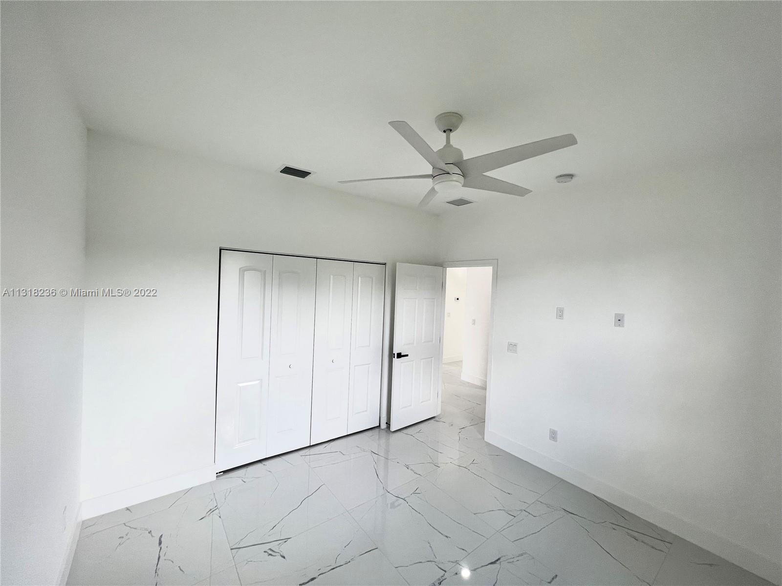 964 Rutherford Lane Haverhill, FL 33415 - Photo 13 of 18 an empty room with a ceiling fan and a window