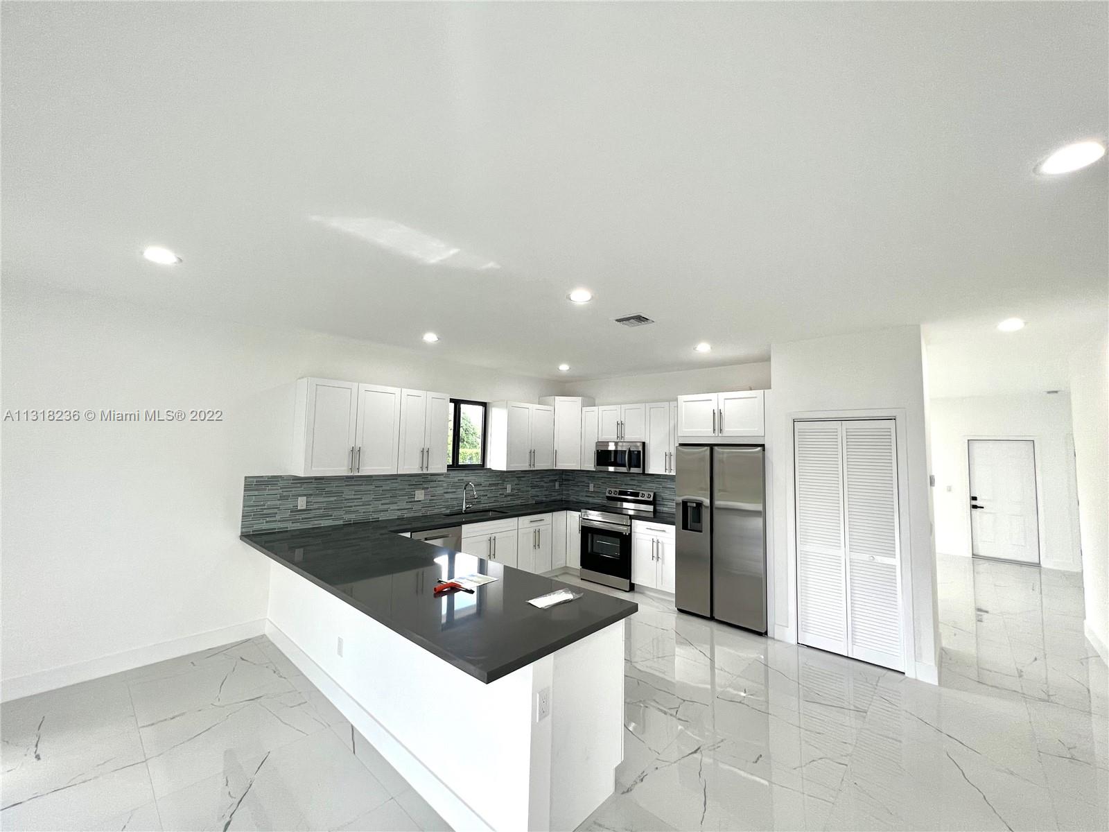 964 Rutherford Lane Haverhill, FL 33415 - Photo 8 of 18 a kitchen with stainless steel appliances granite countertop a sink and a refrigerator