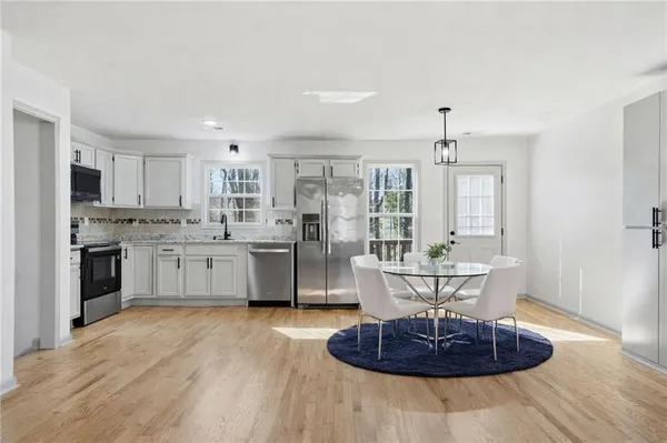 a living room with stainless steel appliances furniture and a kitchen view