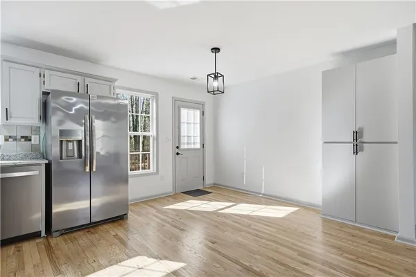 a view of a kitchen with wooden floor electronic appliances and windows