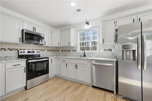 a kitchen with granite countertop a refrigerator stove and sink