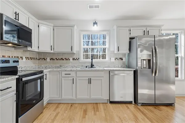 a kitchen with white cabinets stainless steel appliances and a sink