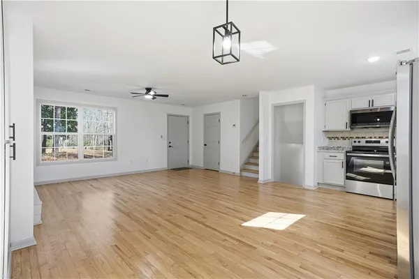 a view of empty room with wooden floor and kitchen