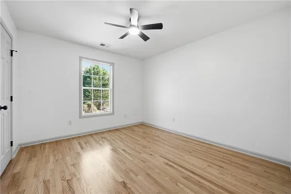 an empty room with wooden floor ceiling fan and windows