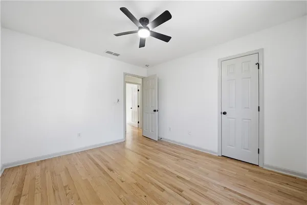 an empty room with wooden floor and a ceiling fan