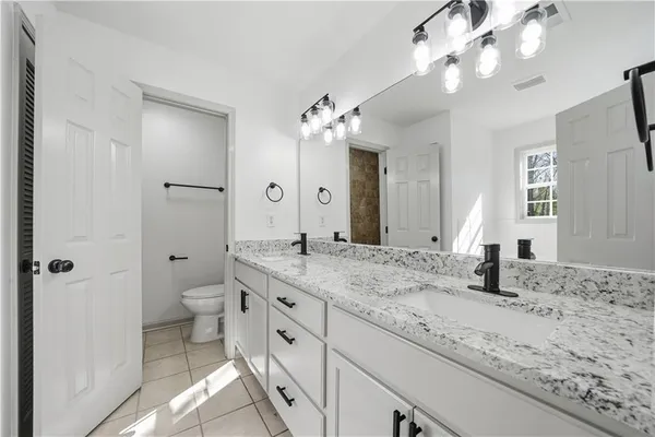 a bathroom with a granite countertop sink a large mirror and a toilet