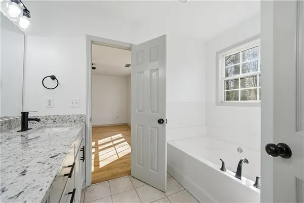 a bathroom with a granite countertop tub sink and mirror