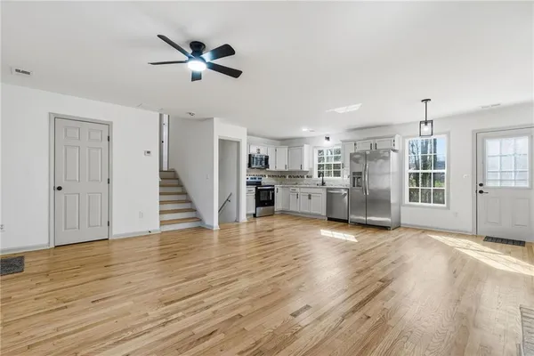 a view of an empty room with wooden floor and a ceiling fan