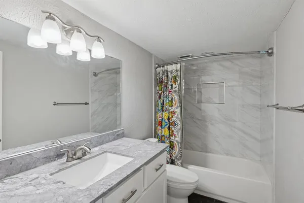 a bathroom with a granite countertop sink a toilet and shower