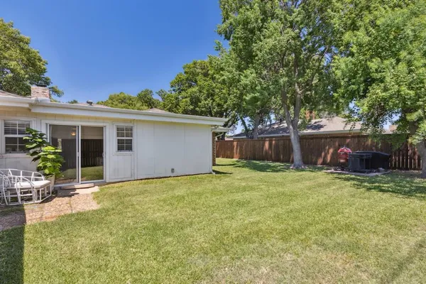 a backyard of a house with table and chairs plants and large tree